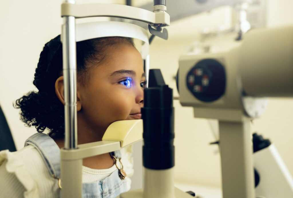 A young girl getting a slit lamp exam at her eye doctor to test her vision