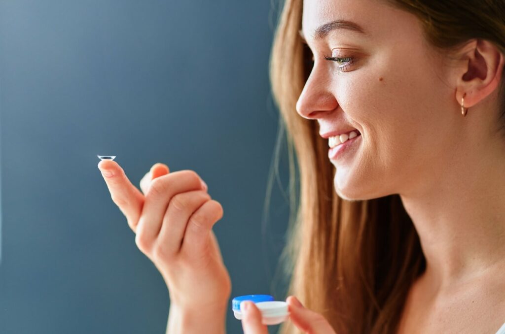 A woman holding an RGP contact lens on the tip of her finger.