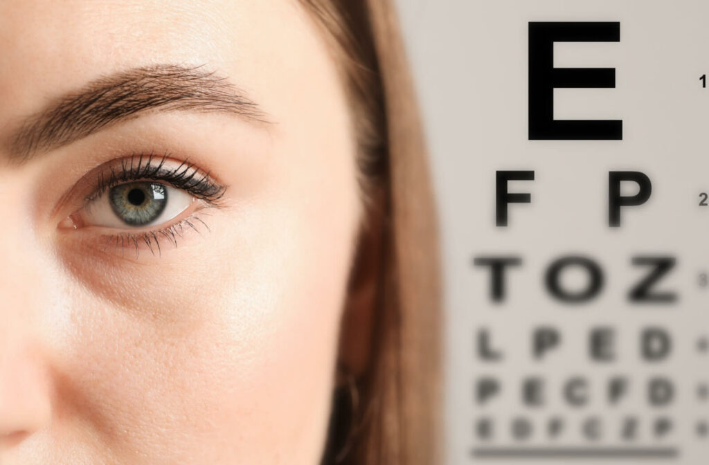 Close-up of a person's eye with a blurry eye chart behind them.