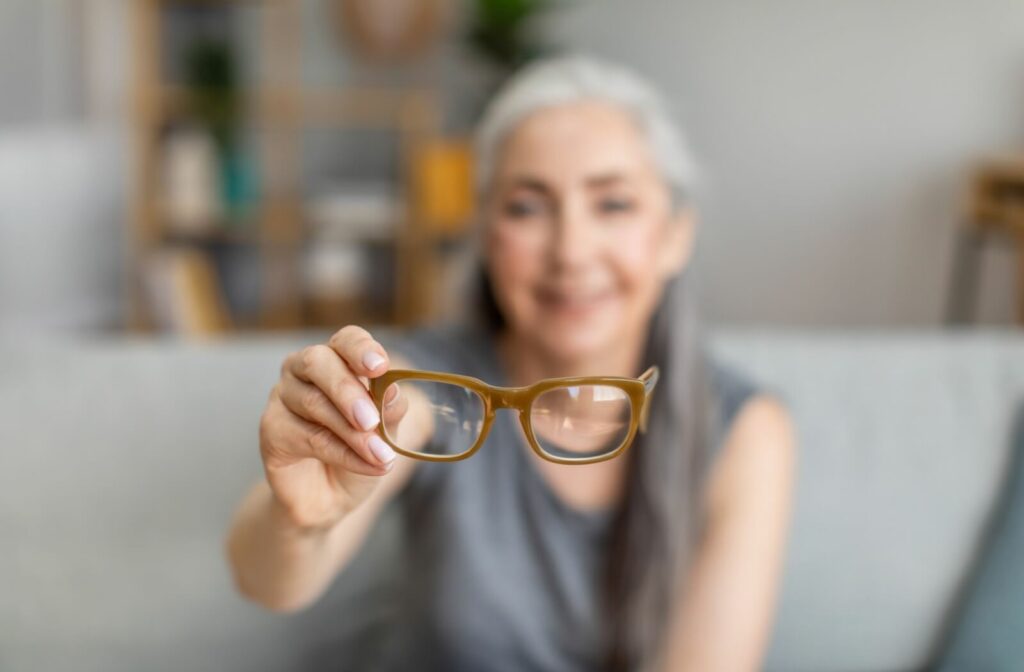 A blurry person sitting on a couch extends their glasses into focus.