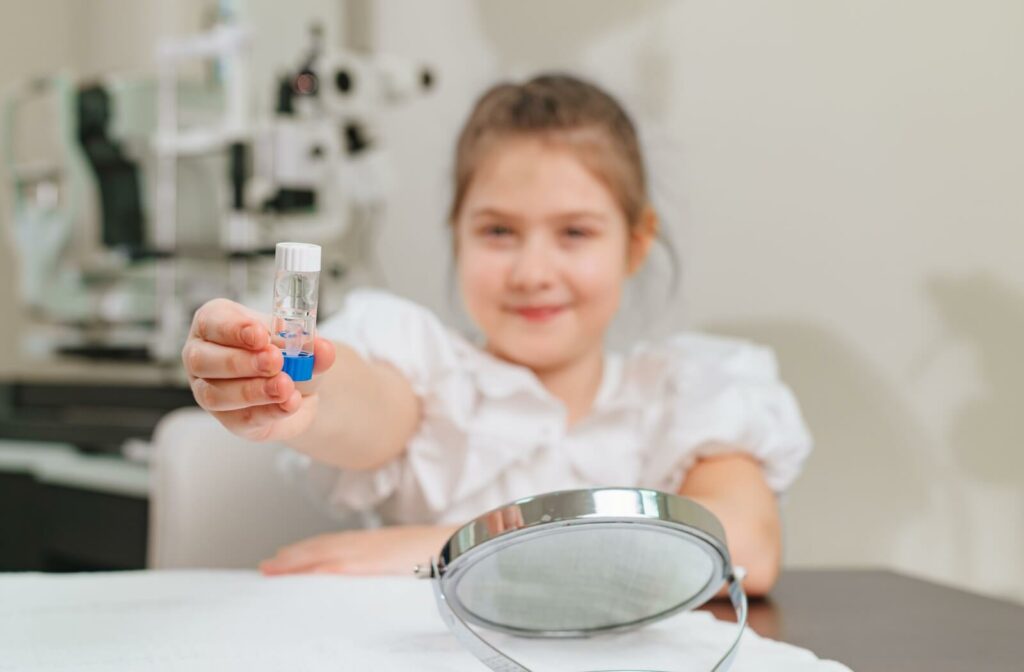 A child holds out a container that stores their ortho-k lenses.
