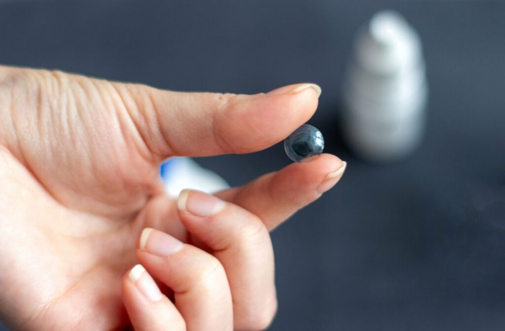 Two fingers carefully hold an ortho-k contact lens.